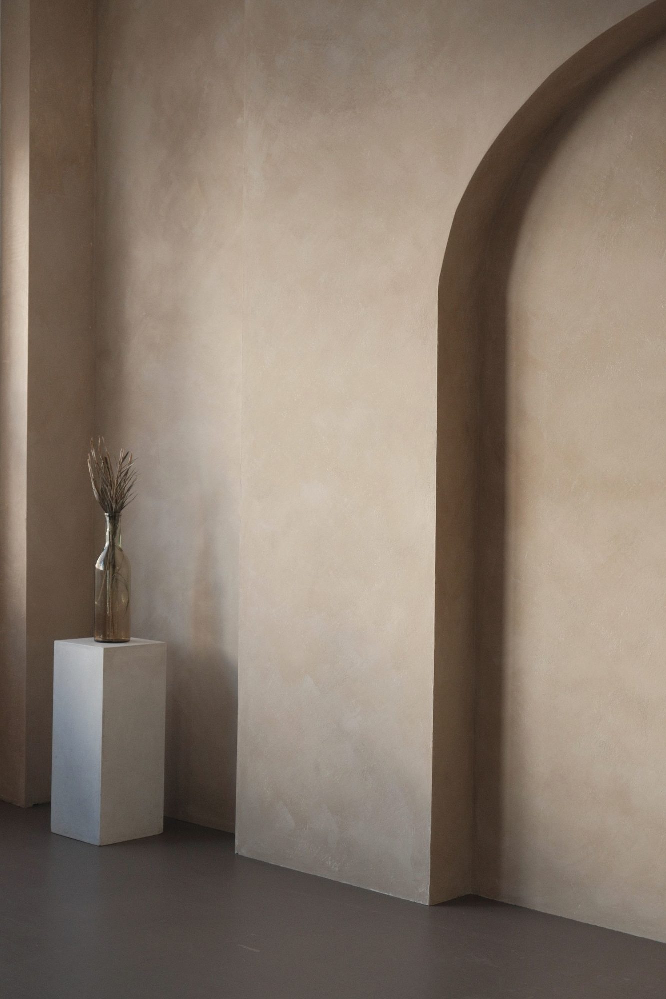 Plaster arch and stone plinth in soft daylight