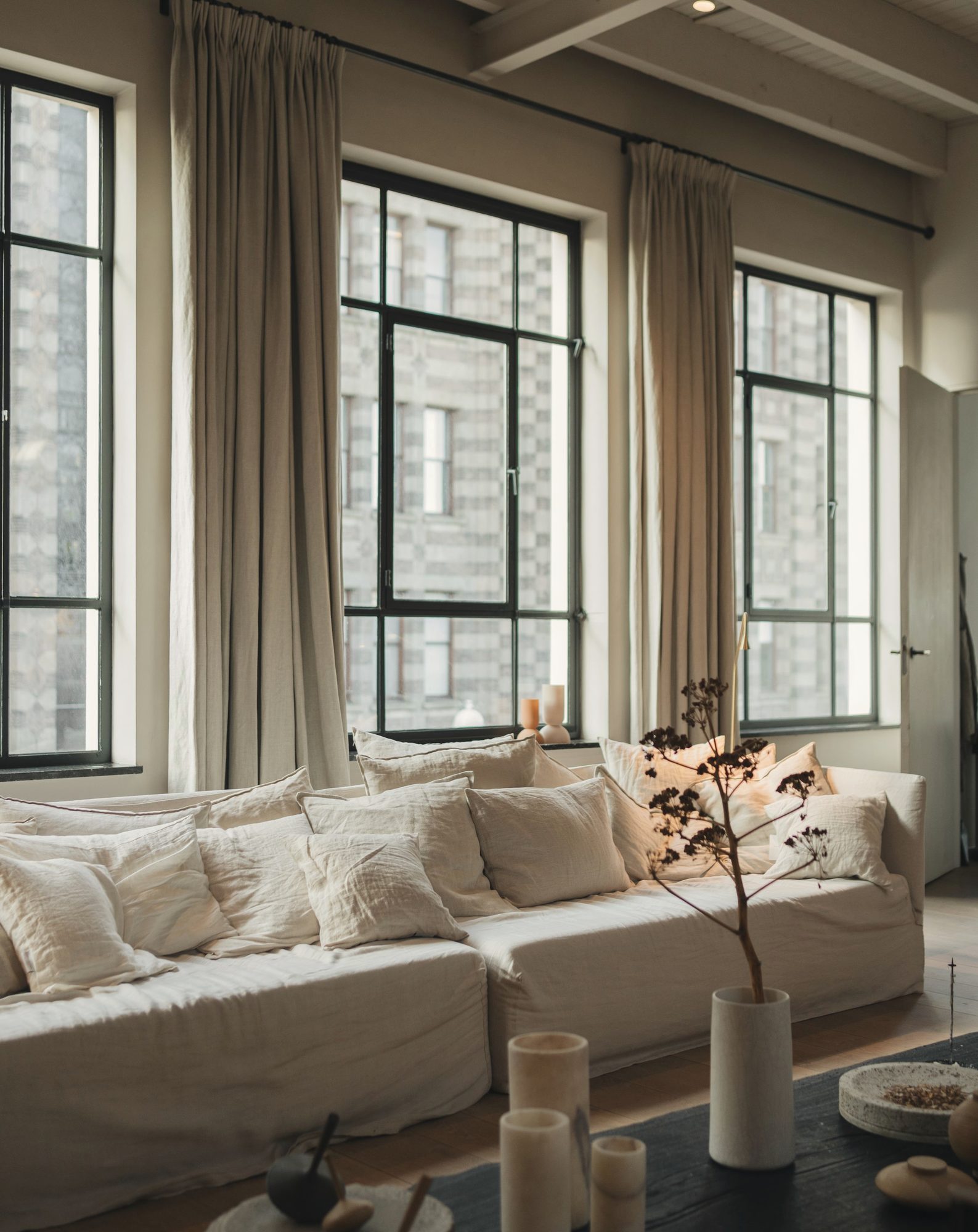 Loft living room with tall steel windows, linen curtains, and a low sofa